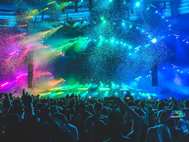 Group of people at concert with confetti and blue, green and pink lights